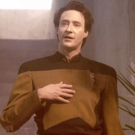 data soong from star trek next genera. he looks disheveled and is smiling at someone off camera